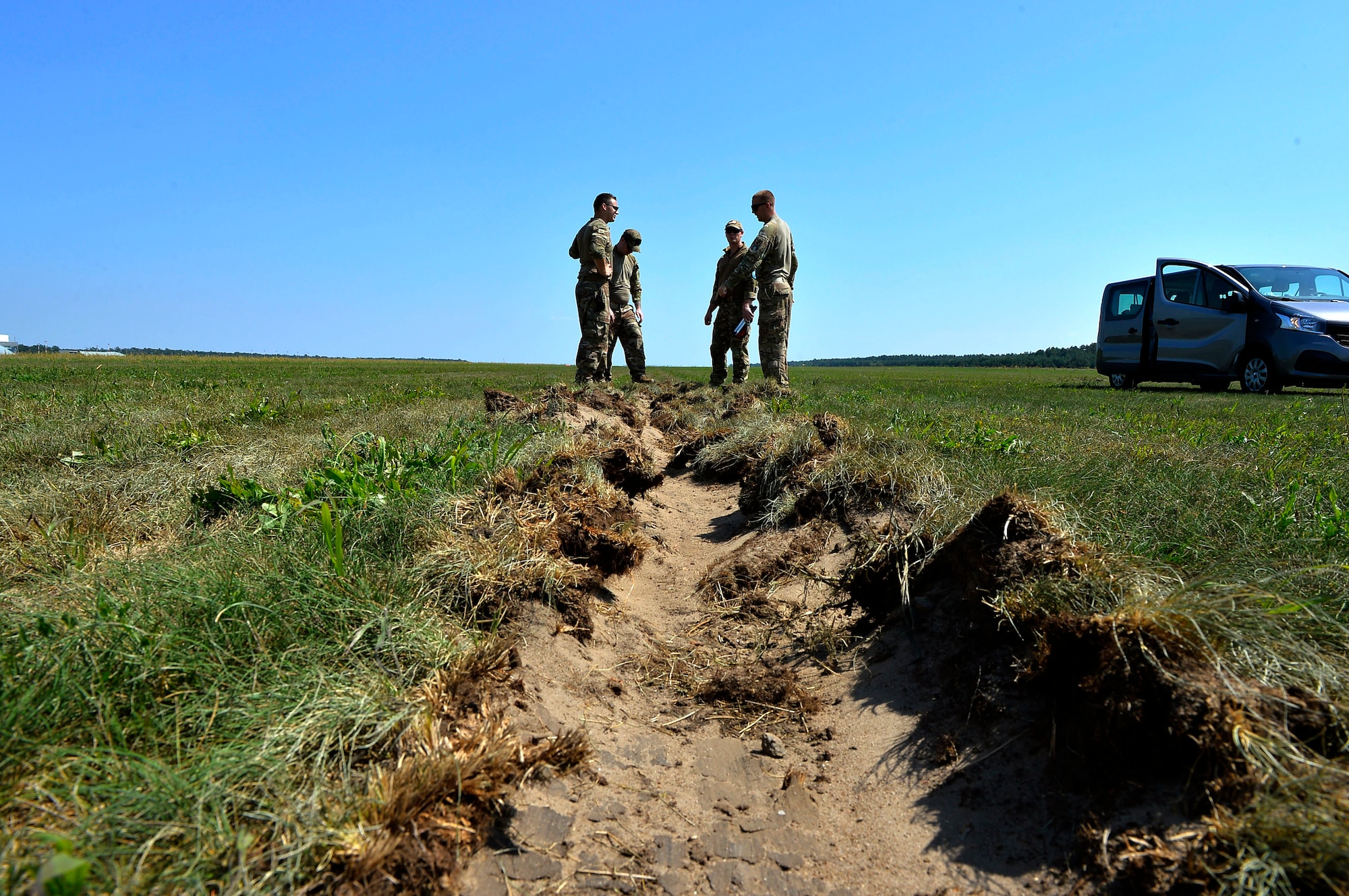 U.S. Airmen assigned to the 435th Contingency Response Group assess a rut generated by an aircraft that landed on Powidz Air Base, Poland, Aug. 1, 2018. Landing zone establishment crews conduct site surveys, assessments, and construction of dirt runways and airdrop targets in a variety of austere environments. (U.S. Air Force photo by Senior Airman Joshua Magbanua)