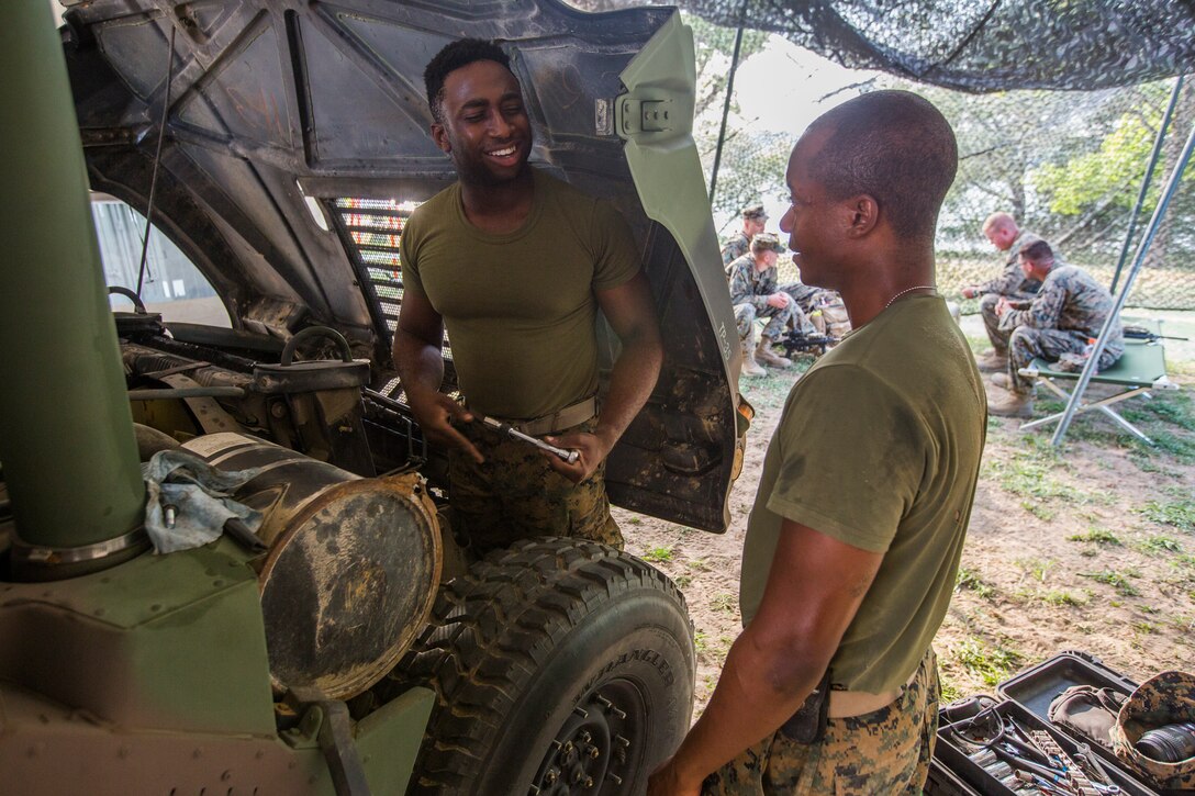 Cpl. Ikechukwe Adiywoe (left) and Pfc. Brandon Peterson (right) both motor transportation mechanics, with 3rd Battalion, 25th Marine Regiment, look over the engine of a Humvee at Camp Grayling, Mich., in support of Exercise Northern Strike, Aug. 5, 2018.