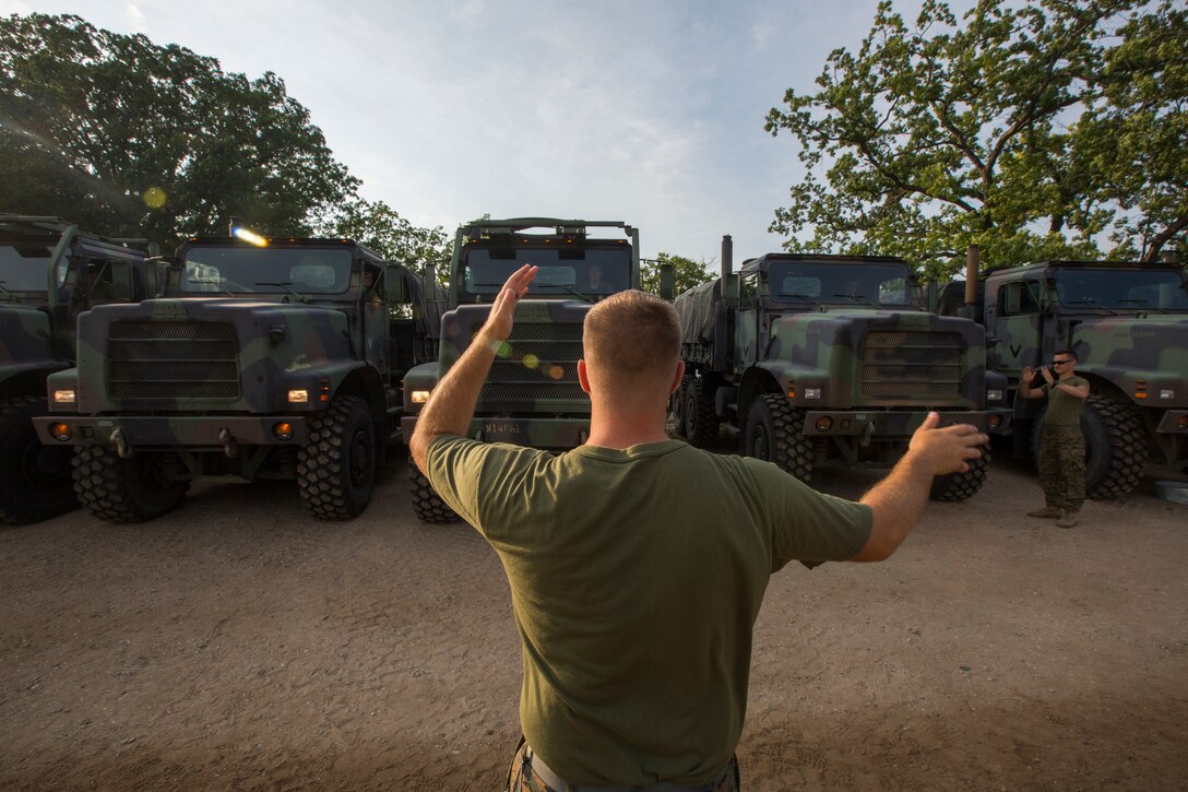 Cpl. Phil Speriando, the line non-commissioned officer in charge, with Truck Company, Headquarters Battalion, out of Erie, Pa., aligns 7-ton trucks at Camp Grayling, Mich., in support of Exercise Northern Strike, Aug. 5, 2018.