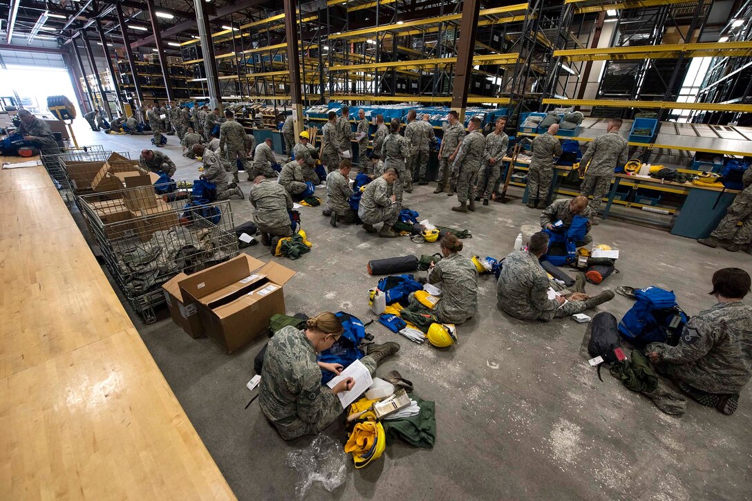 Airmen prepare their emergency response and fire equipment bags.