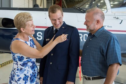 The parents of 2nd Lt. Nickolas Brandt, Pilot Training Next student, pin on his aeronautical wings during his graduation August 3, 2018, at the Armed Forces Reserve Center, Austin, Texas. PTN is a program to explore and potentially prototype a training environment that integrates various technologies to produce pilots in an accelerated, cost efficient, learning-focused manner.