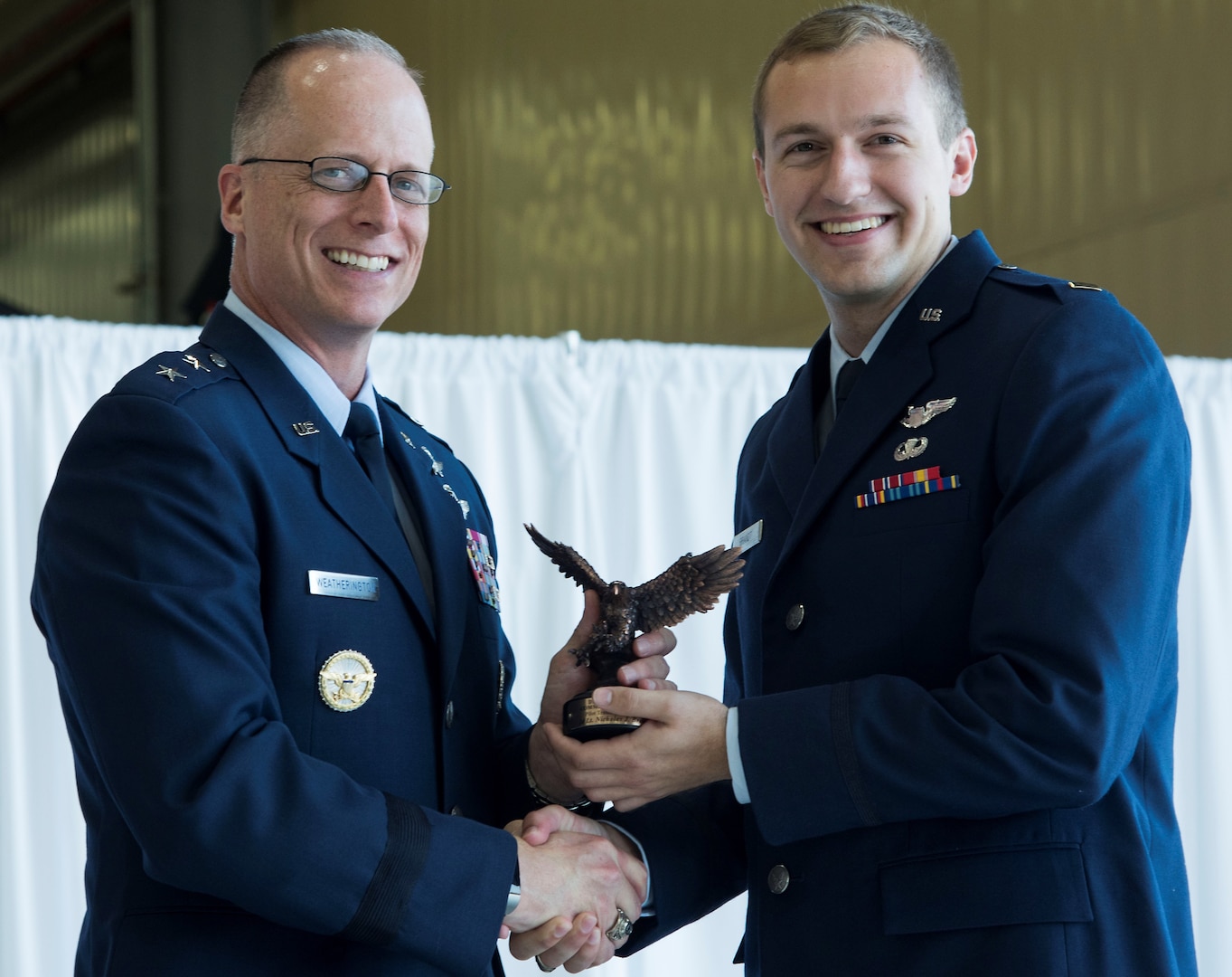 U.S. Air Force 2nd Lt. Nicholas Brandt (right), Pilot Training Next graduate, receives the commander’s graduate award during the first ever Pilot Training Next graduation August 3 at the Texas Army National Guard Hangar in Austin, Texas. PTN is a program to explore and potentially prototype a training environment that integrates various technologies to produce pilots in an accelerated, cost efficient, learning-focused manner.