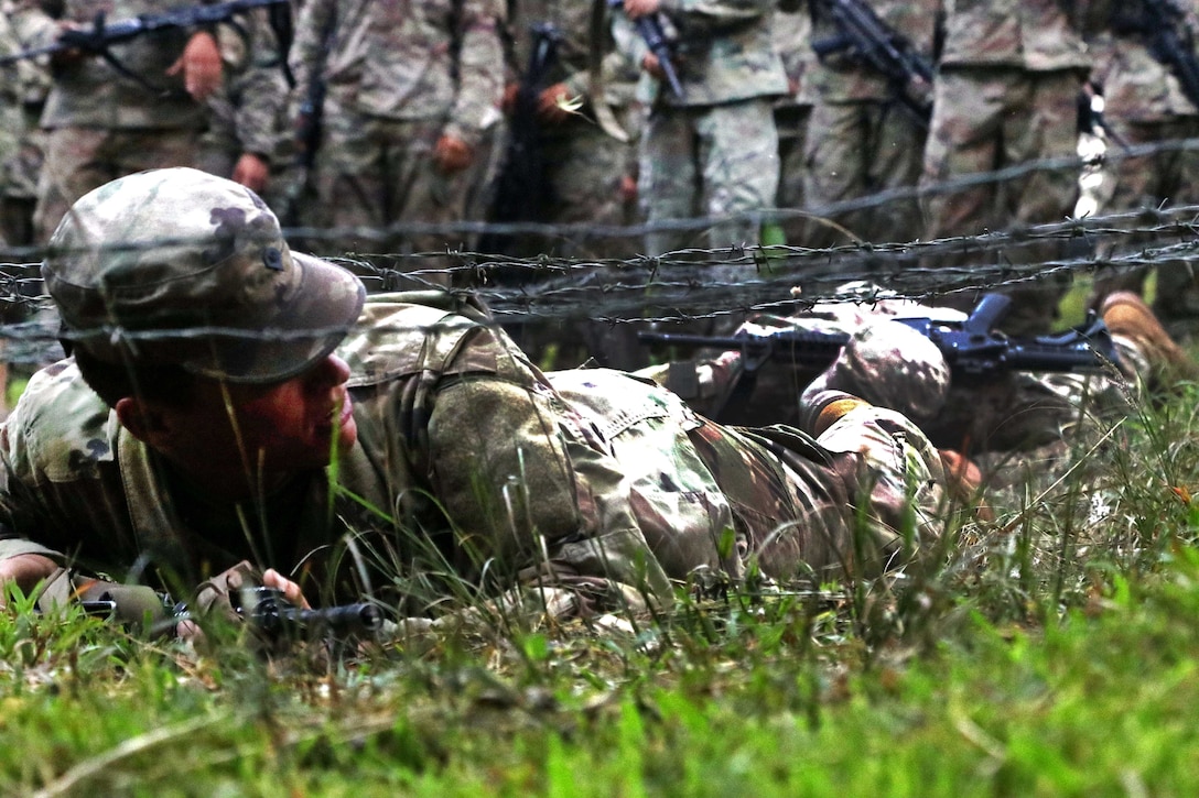 U.S. soldiers practice low crawling under the concertina wire obstacle.