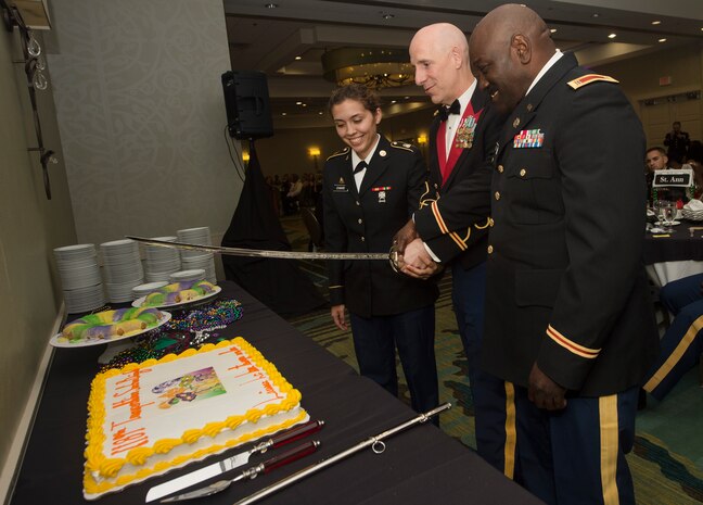 From left to right, U.S. Army Pvt. Christina Chavis, 82nd Distribution Deployment Support Battalion, Col. Daniel Keller, 1189th Transportation Surface Battalion outgoing commander, and Chief Warrant Officer Curtis Wilson, 1189th TSB mobility warrant officer, cut a cake during the 1189th TSB Mardi Gras Masquerade Ball at the Crowne Plaza Charleston Airport Hotel Aug. 4, 2018, in North Charleston, S.C. The youngest and oldest Soldier in attendance were selected to cut the cake with Keller.