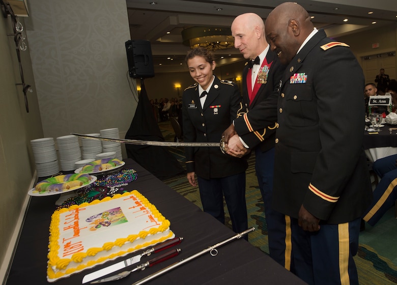 From left to right, U.S. Army Pvt. Christina Chavis, 82nd Distribution Deployment Support Battalion, Col. Daniel Keller, 1189th Transportation Surface Battalion outgoing commander, and Chief Warrant Officer Curtis Wilson, 1189th TSB mobility warrant officer, cut a cake during the 1189th TSB Mardi Gras Masquerade Ball at the Crowne Plaza Charleston Airport Hotel Aug. 4, 2018, in North Charleston, S.C. The youngest and oldest Soldier in attendance were selected to cut the cake with Keller.