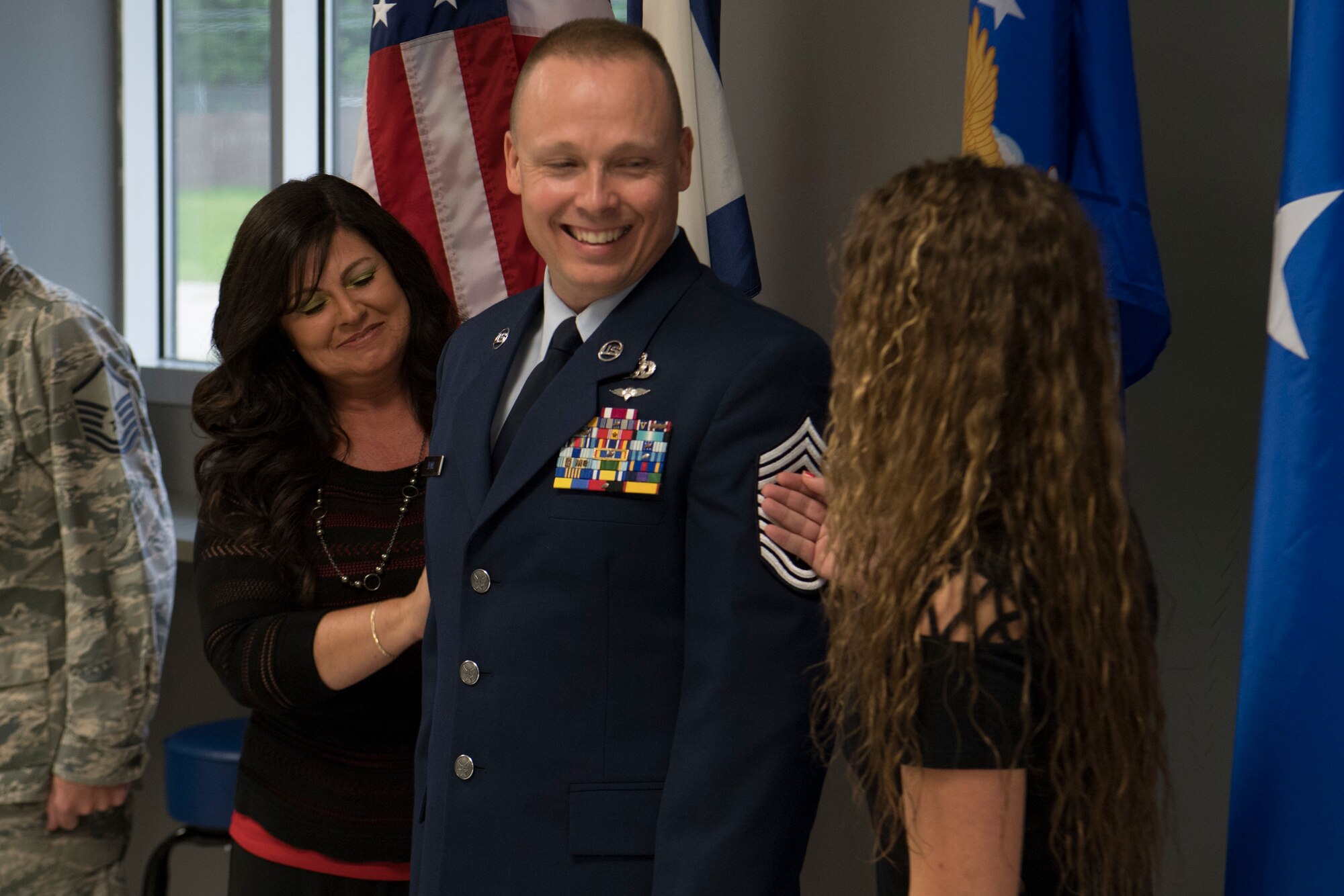 Chief Master Sgt. Jason Evans, 130th Force Support Squadron Chief, gets his new stripes tacked on by his wife and daughter Aug. 4, 2018 at McLaughlin Air National Guard Base, Charleston, W.Va.(U.S. Air National Guard Photo by Airman 1st Class Caleb Vance)