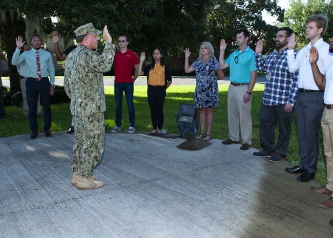 PANAMA CITY, Florida - Naval Surface Warfare Center Panama City Division Commanding Officer Capt. Aaron Peters, USN, administers the oath of office to 11 newly hired federal civil service employees at the flagpole Aug. 6, 2018. U.S. Navy photos by Eddie Green