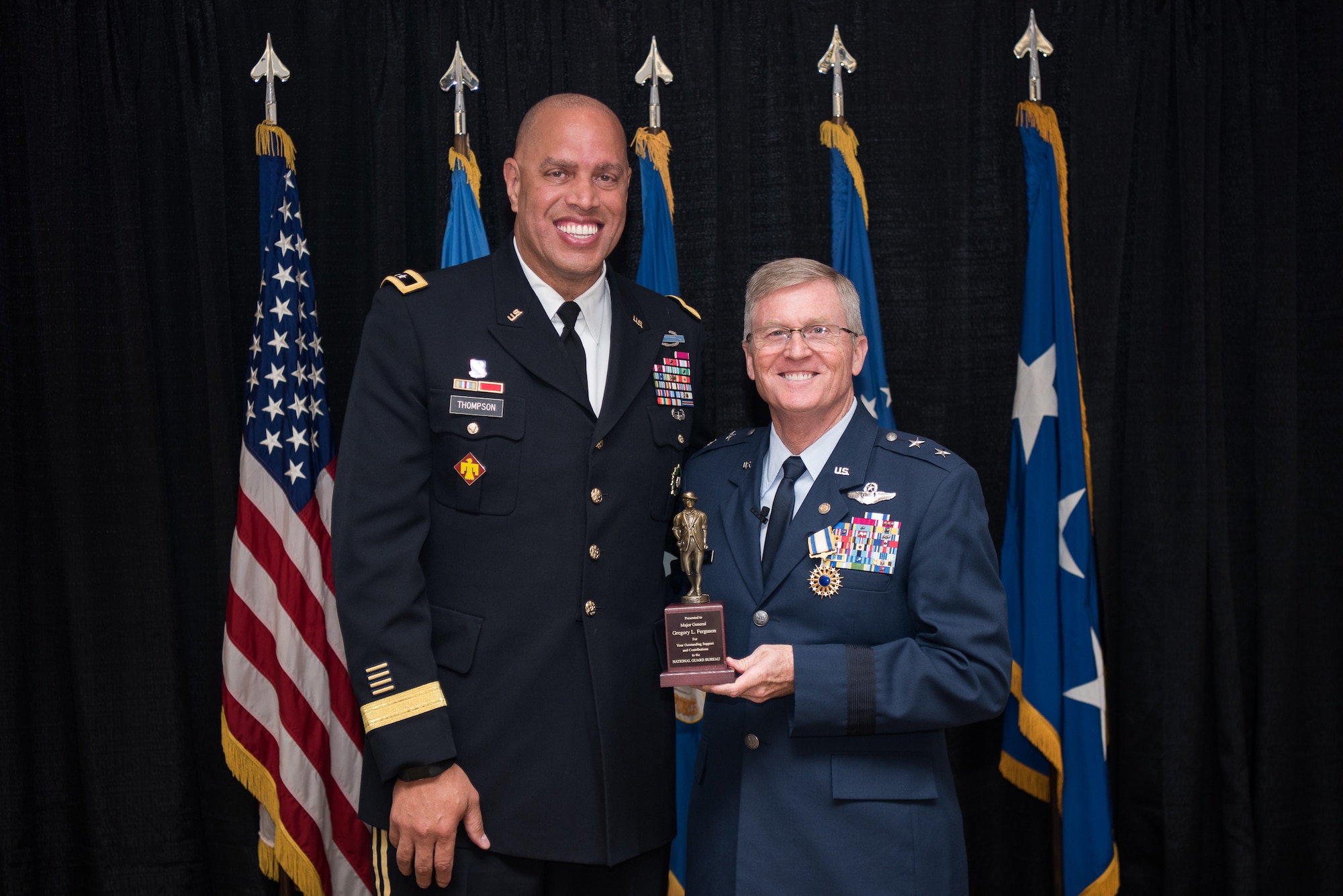 Maj. Gen. Michael C. Thompson (lfet), Oklahoma adjutant general, Joint Force Headquarter, Oklahoma City, presents a National Guard Bureau minuteman statue to Maj. Gen. Gregory L. Ferguson (right), Air National Guard assistant to the commander, Air Force Special Operations Command (AFSOC), Hurlbert Field, Florida, during Ferguson's retirement ceremony at Will Rogers Air National Guard Base in Oklahoma City, Aug. 4, 2018.