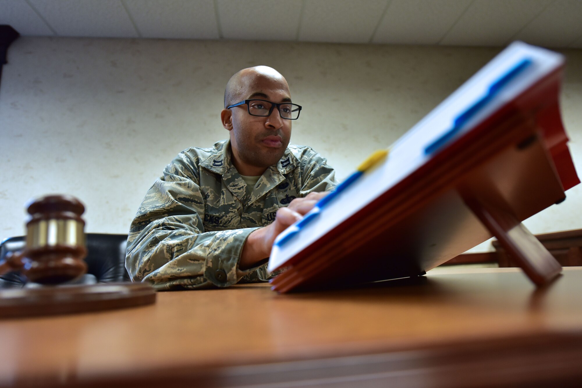 Man sits at desk and reads book.