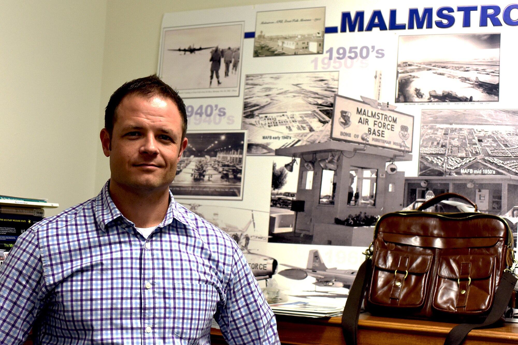Troy Hallsell, 341st Missile Wing historian, poses next to books and posters in the historian’s office at the 341st Missile Wing headquarters building August 7, 2018, at Malmstrom Air Force Base, Mont. Hallsell has taken up residence as the new base historian. (U.S. Air Force photo by Kiersten McCutchan)