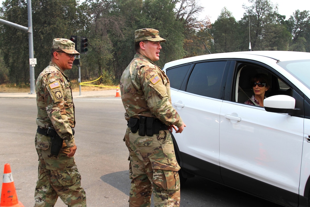 Soldiers help local residents with driving directions at a traffic control point.