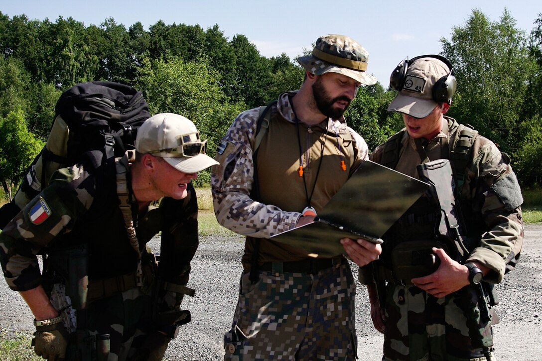 A Latvian soldier, center, reviews scores with a French sniper team.