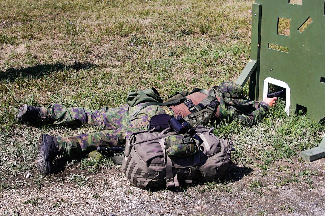 A Finnish sniper fires his handgun from behind cover engaging targets.