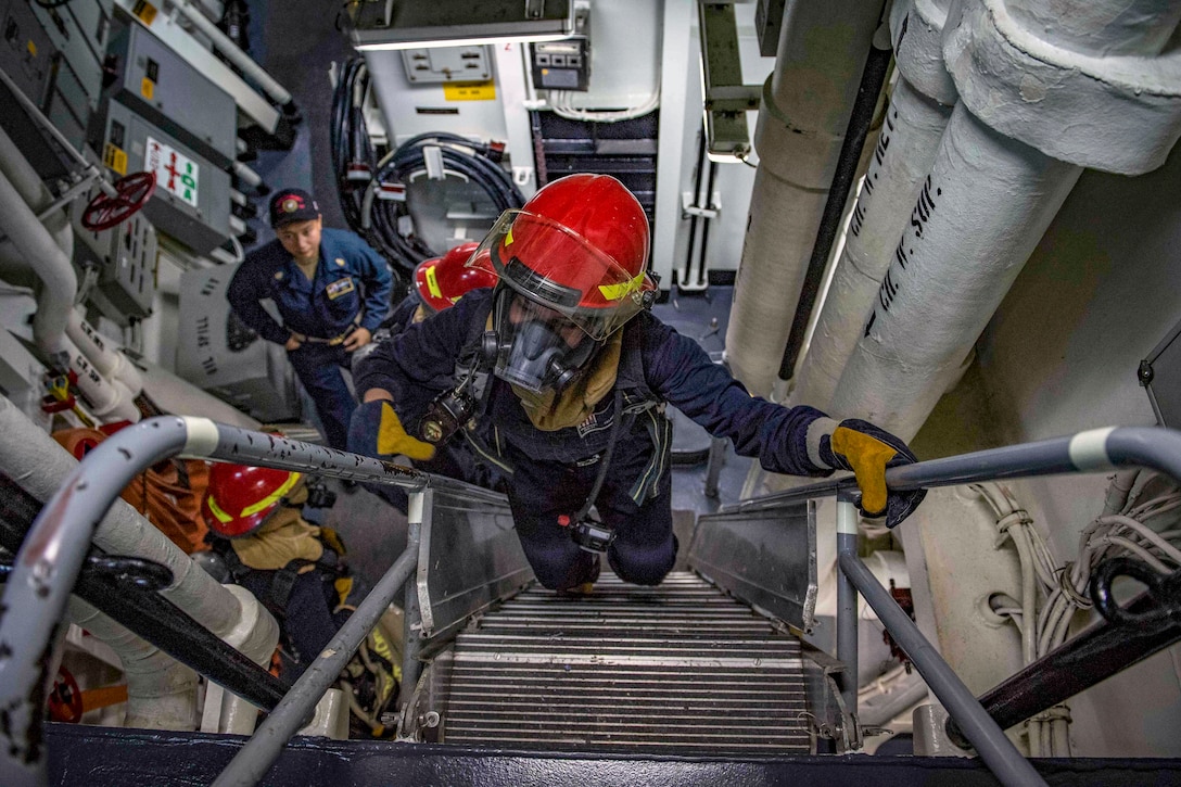 Sailors walk up a set of steps.