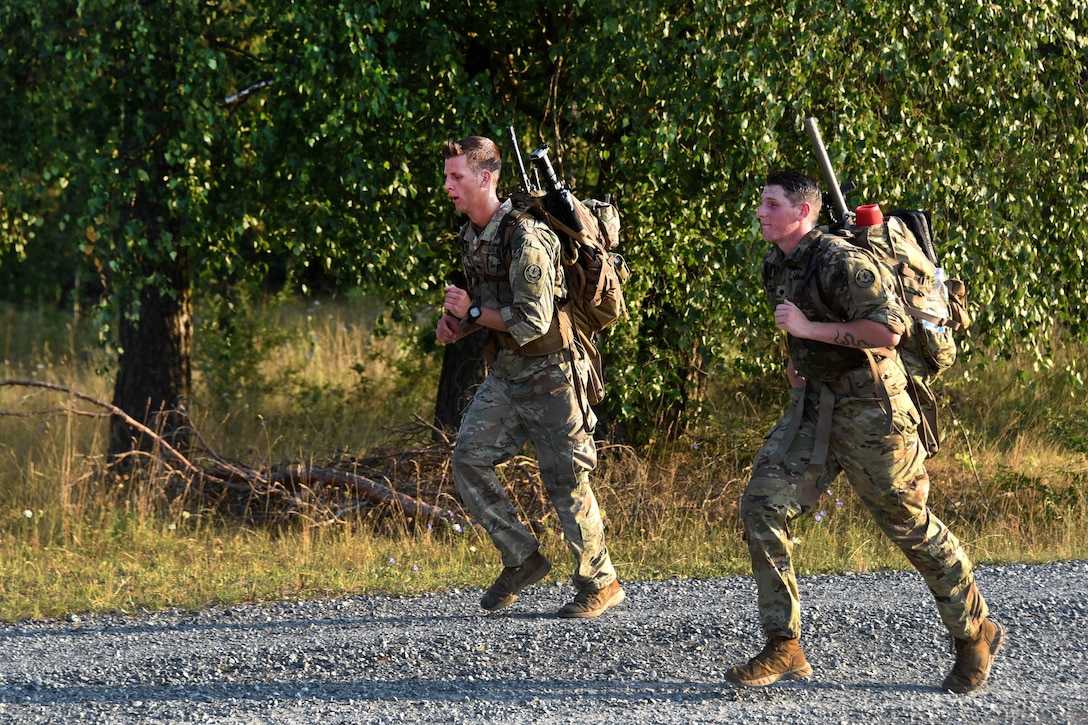 Two U.S. soldiers and NATO sniper teams participate in the ruck march.