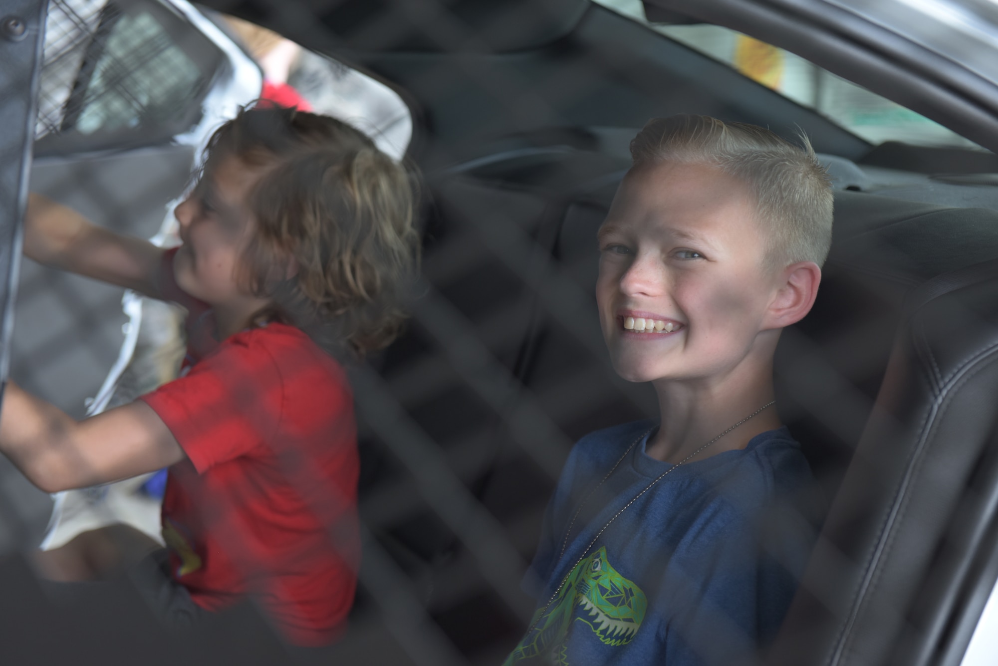A boy smiles in the back of a patrol car during the “kids deployment line” at RAF Mildenhall, England, Aug. 3, 2018. Security Forces was one of 22 agencies who participated in the event to teach kids what life is like while deployed. (U.S. Air Force photo by Senior Airman Kelly O’Connor)