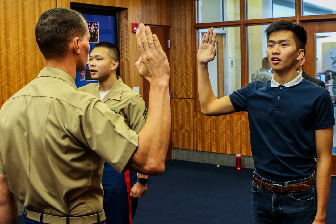 Staff Sgt. Jamescarlo Eco, staff noncommissioned officer in charge of Recruiting Substation Savannah, Recruiting Station Jacksonville, re-enlists as his brother, Marvic Eco, a poolee with RSS Jacksonville, enlists for the first time. The Eco brothers swore into the Marine Corps joined by their parents on July 26, 2018. (U.S. Marine Corps photo by Sgt. Tony Simmons)
