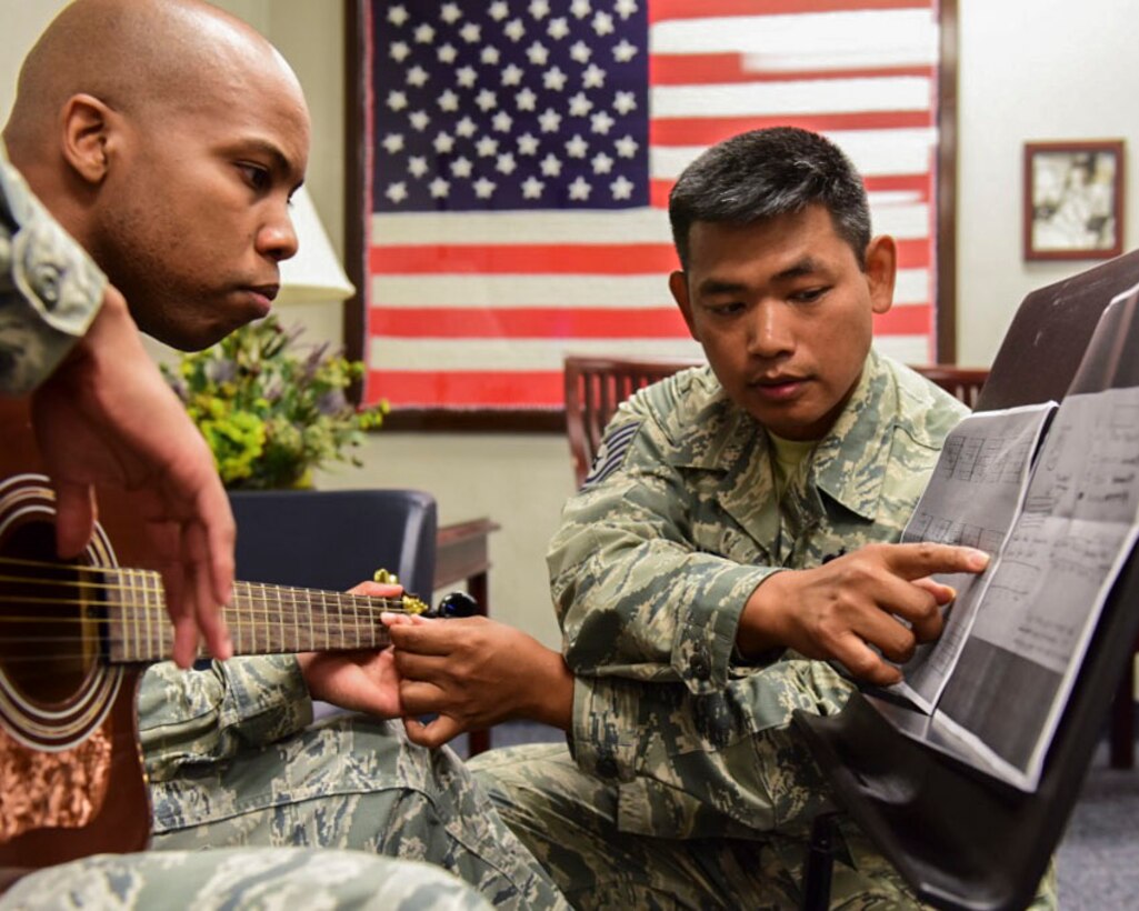 From left, U.S. Air Force Staff Sgt. Michael Burks, 1st Maintenance Squadron precision measurement equipment lab technician, and U.S. Air Force Tech. Sgt. Daniel Santos, U.S. Air Force Heritage Band of America guitarist, learn guitar chords at Joint Base Langley-Eustis, Virginia, July 31, 2018.