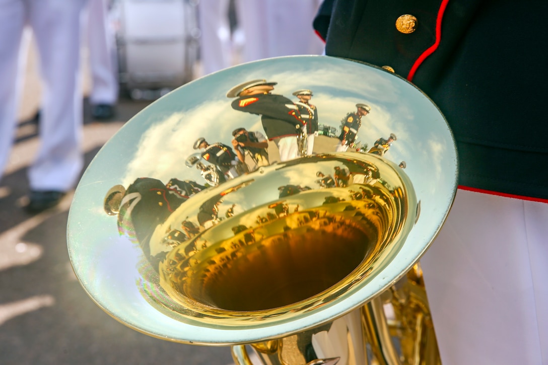 Band members are reflected in the surface of an instrument.