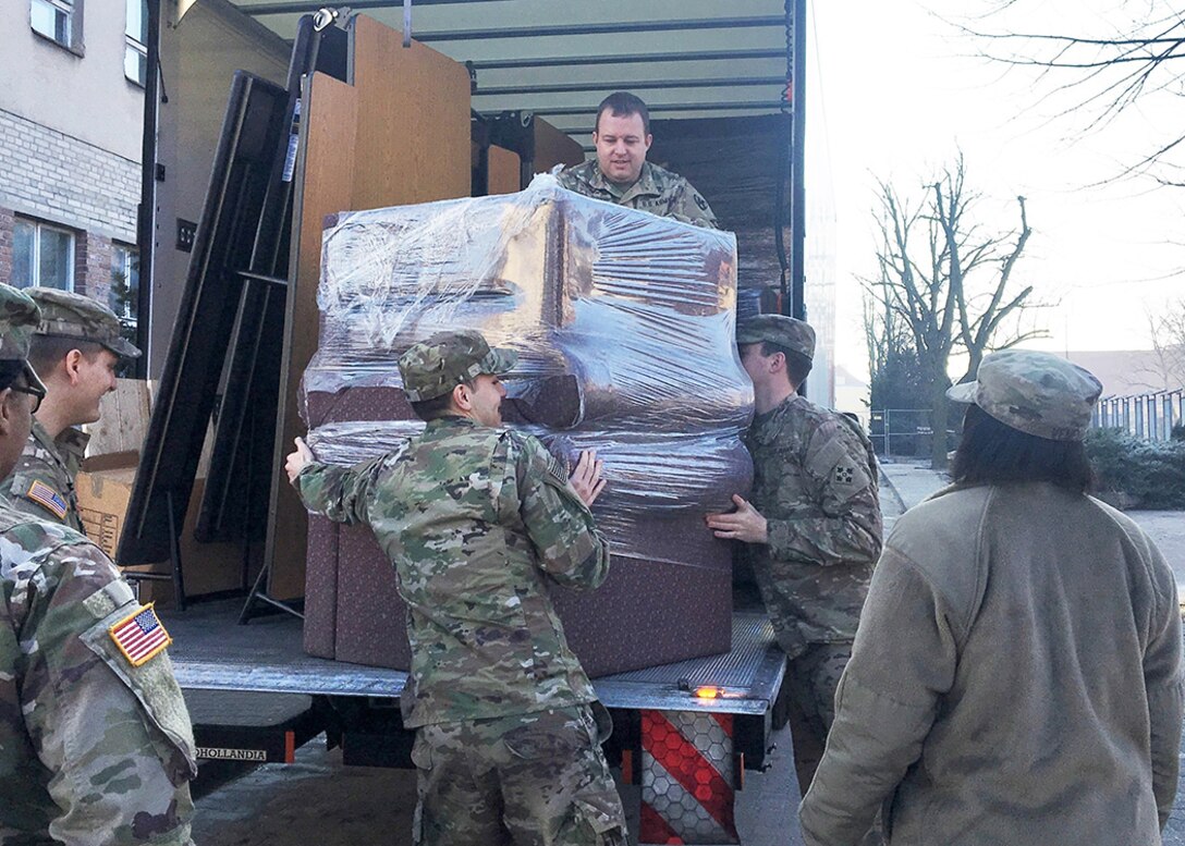 Capt. Jason M. Spalding (top center), 21st Theater Sustainment Command liaison officer, Mission Command Element (MCE) helps unload furniture  to improve the quality of life.