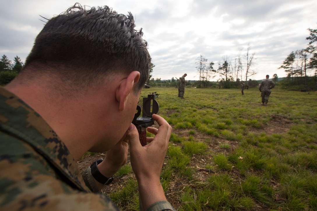 Cpl. Cody Lindsey, a mortarman with Lima Company, 3rd Battalion, 25th Marine Regiment, aligns the front and rear aiming stakes with a compass during Exercise Northern Strike at Camp Grayling, Mich., Aug. 7, 2018.
