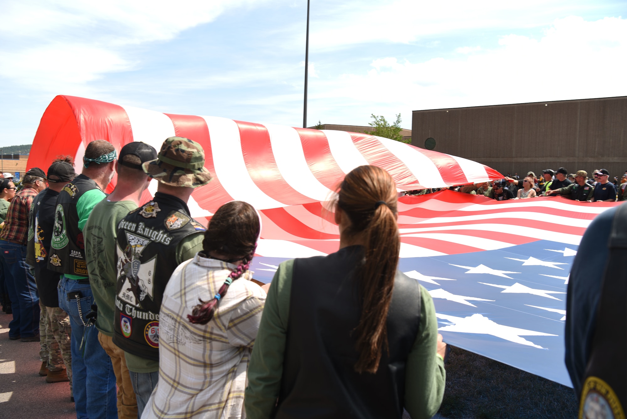 Participants from the Dakota Thunder Run fold a flag flown by retired Army 1st Sgt., Dana Bowman, a former Golden Knight parachute team member, as he parachuted to the ground at Sturgis, S.D., Aug. 7, 2018. Over 150 participants rode 53 miles from Ellsworth AFB to the Sturgis Motorcycle Rally, where they helped kick off Military Appreciation Day events. (U.S. Air Force photo by Airman 1st Class Thomas Karol)