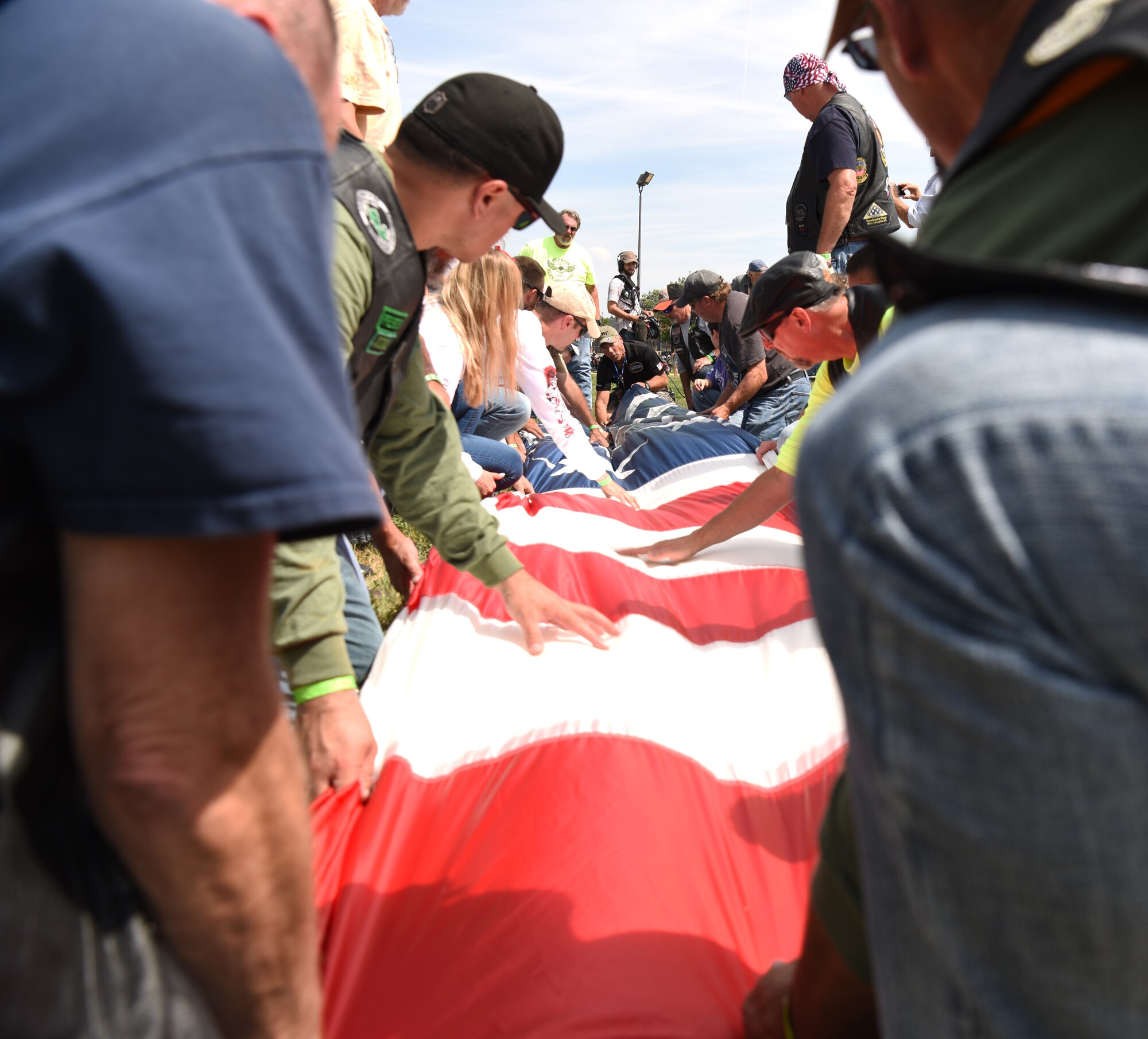 Attendees of the Dakota Thunder Run fold a large U.S. flag at Sturgis, S.D., Aug. 7, 2018. The flag was flown in by retired Army 1st Sgt., Dana Bowman, a former Golden Knight parachute team member, who parachuted to the ground at the Sturgis Motorcycle Rally during their Military Appreciation Day. (U.S. Air Force photo by Airman 1st Class Thomas Karol)