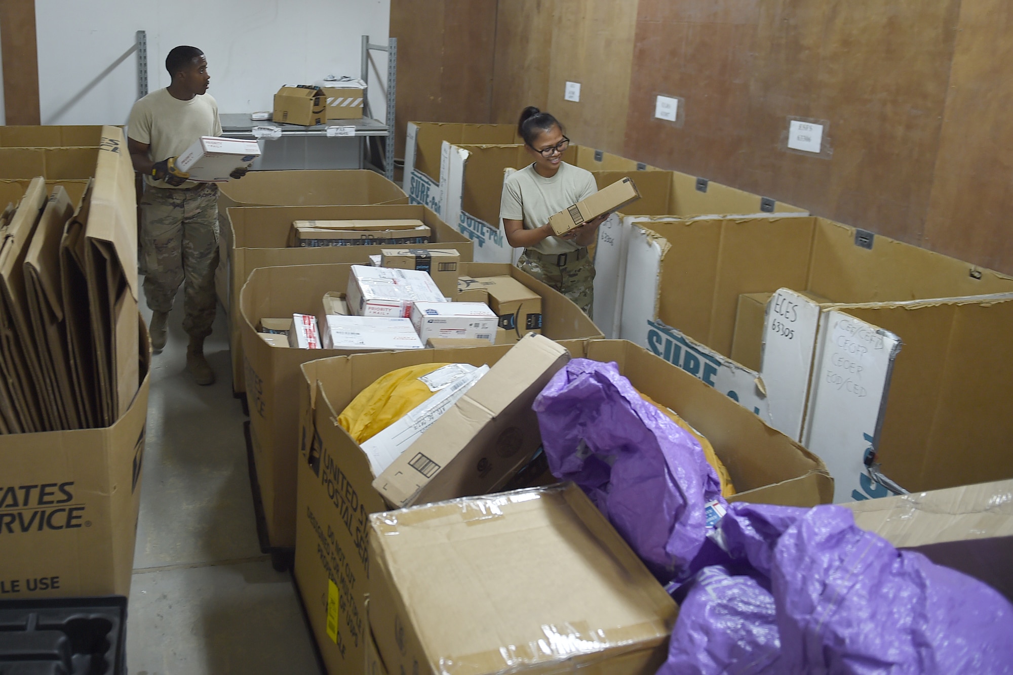 Two Airmen sort through big boxes of mail