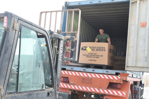 A Marine stands in the back of a large mail truck