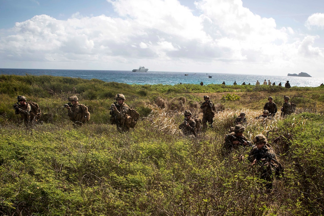 Marines maneuver toward their objective after disembarking assault amphibious vehicles.