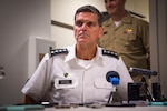 A military commander sits behind a microphone as he talks to reporters.