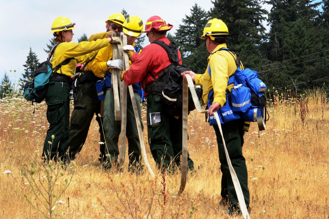 Soldiers practice how to properly carry a fire hose during training.