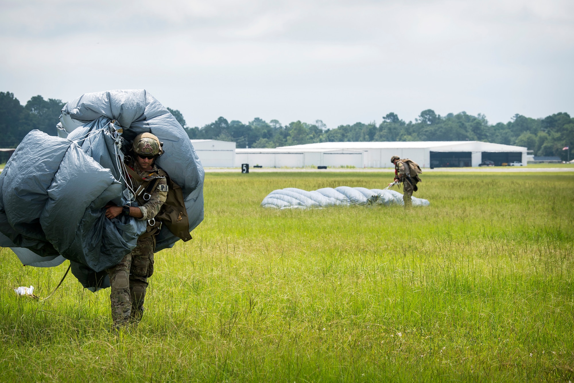 A Pararescueman (PJ) from the 38th Rescue Squadron (RQS), carries a parachute after a static-line jump, July 24, 2018, in Valdosta, Ga. PJs performed static-line jumps to maintain their jump proficiency qualifications. The mission of the 38th RQS is to employ combat ready rescue officers and pararescuemen to support units worldwide. (U.S. Air Force photo by Airman 1st Class Eugene Oliver)