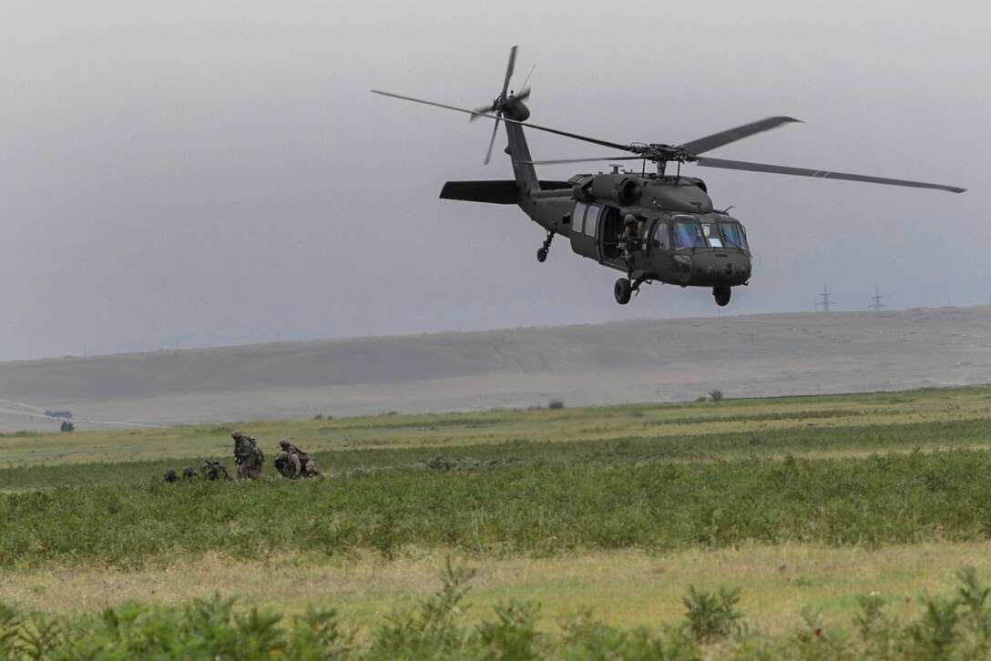 U.S. and NATO troops dismount a helicopter while conducting an air assault exercise.