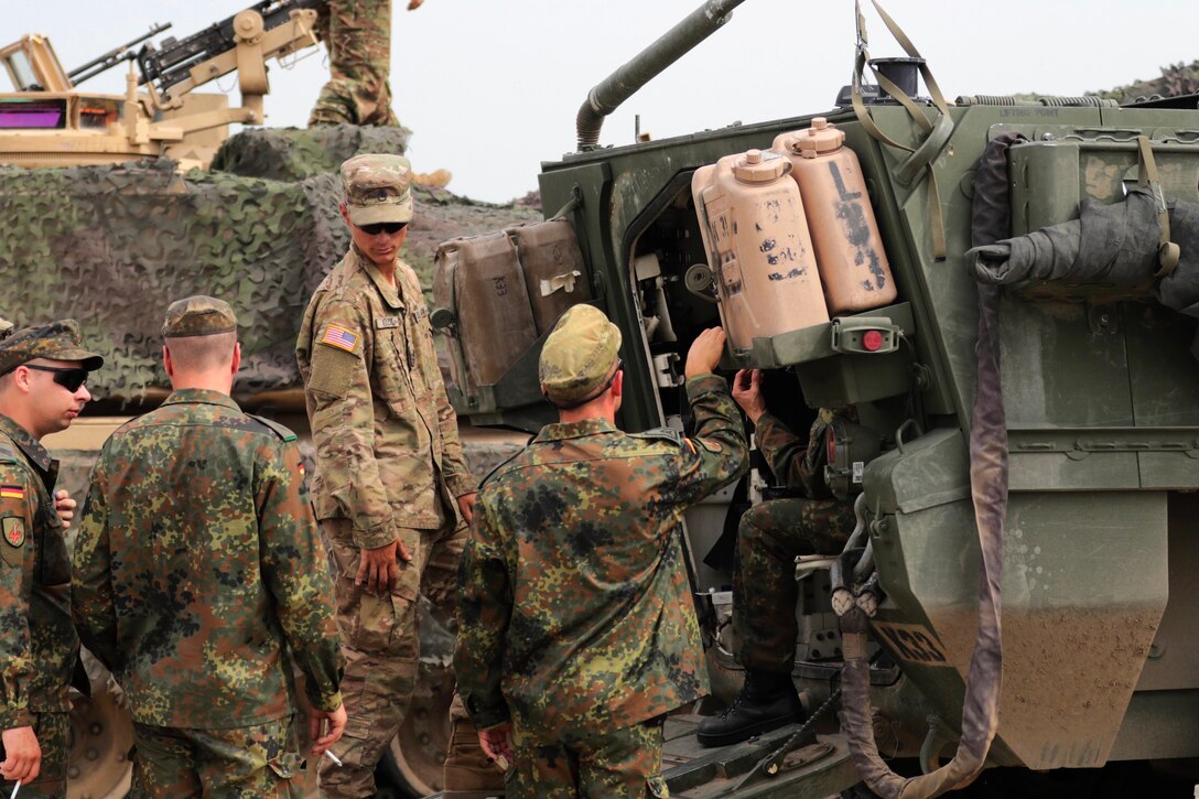 A U.S. soldier listens to questions from German soldiers about the M1126 Stryker combat vehicle.