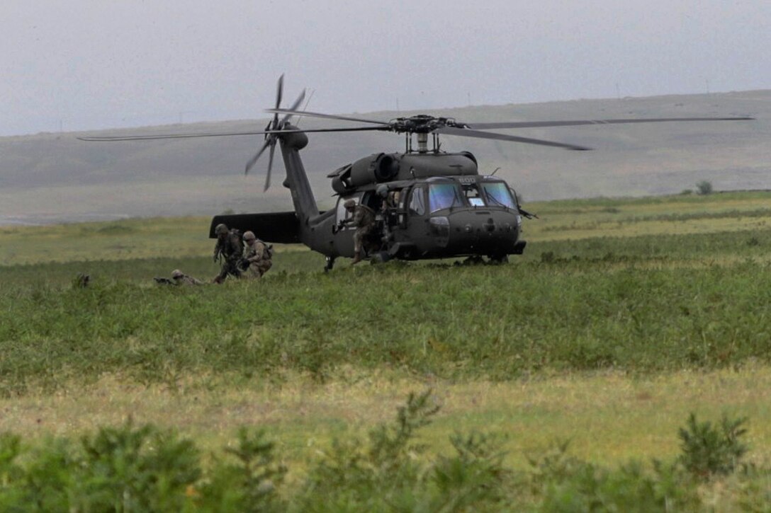 U.S. soldiers dismount a helicopter while conducting an air assault exercise.