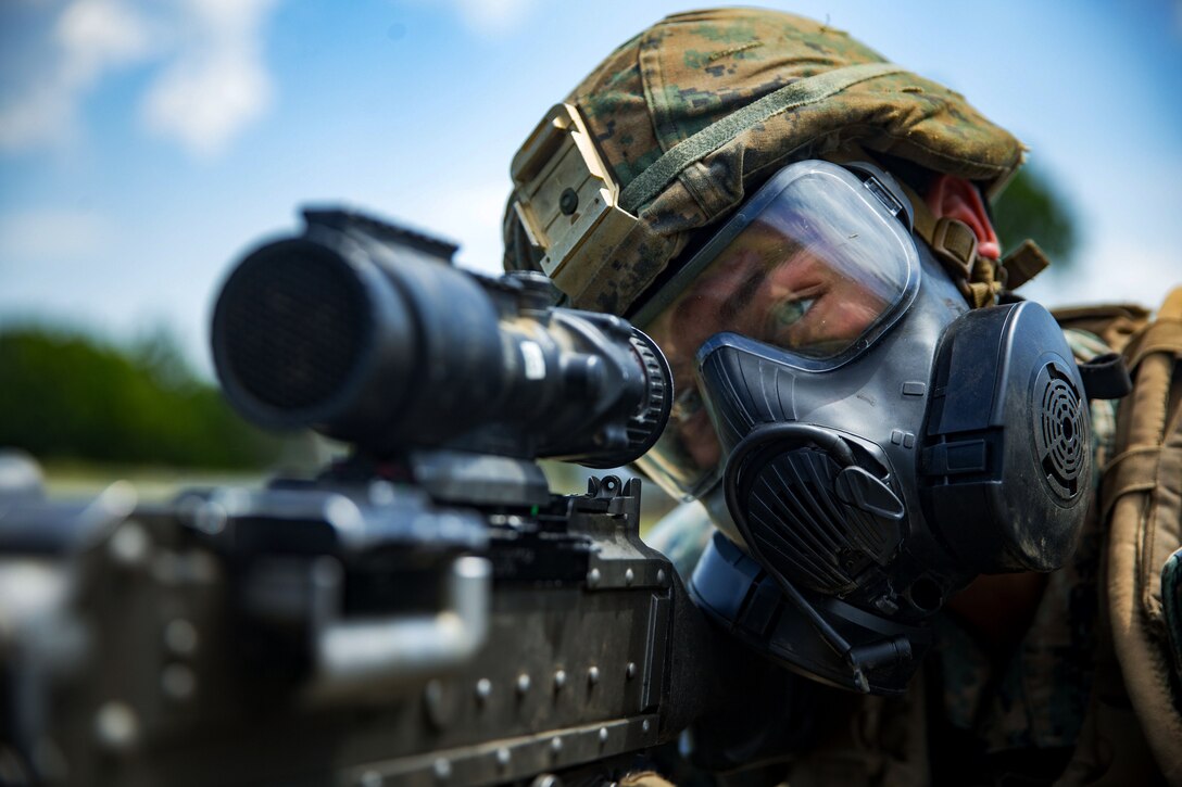 A Marine performs target practice while wearing his gas mask during training.