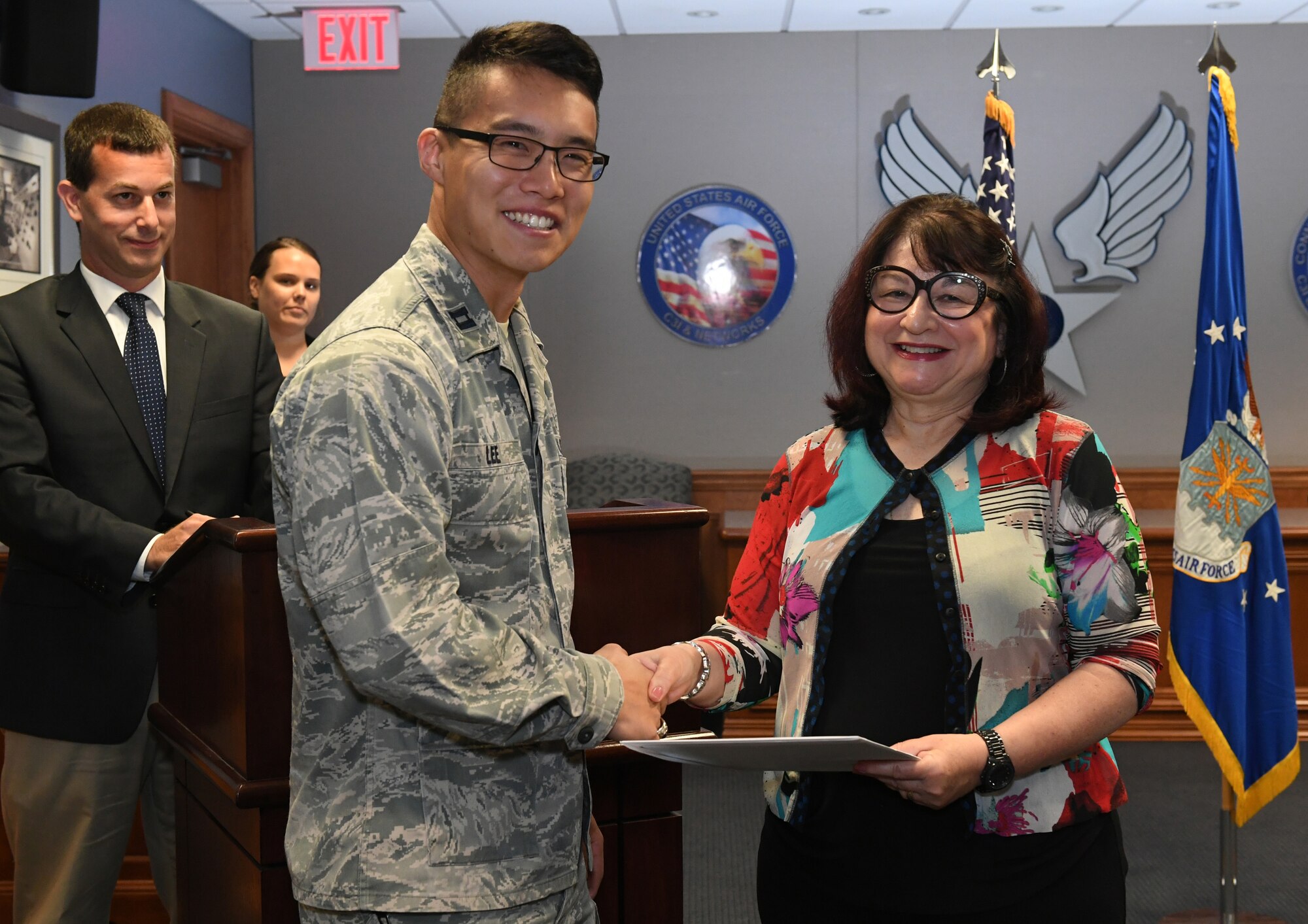 Capt. Taeyoung Lee, a program manager under Battle Management, accepts a certificate of completion from Catherine Kendrick, dean of the Division of Online and Continuing Education at the University of Massachusetts Lowell, during a program manager seminar graduation ceremony at Hanscom Air Force Base, Mass. Aug. 8.