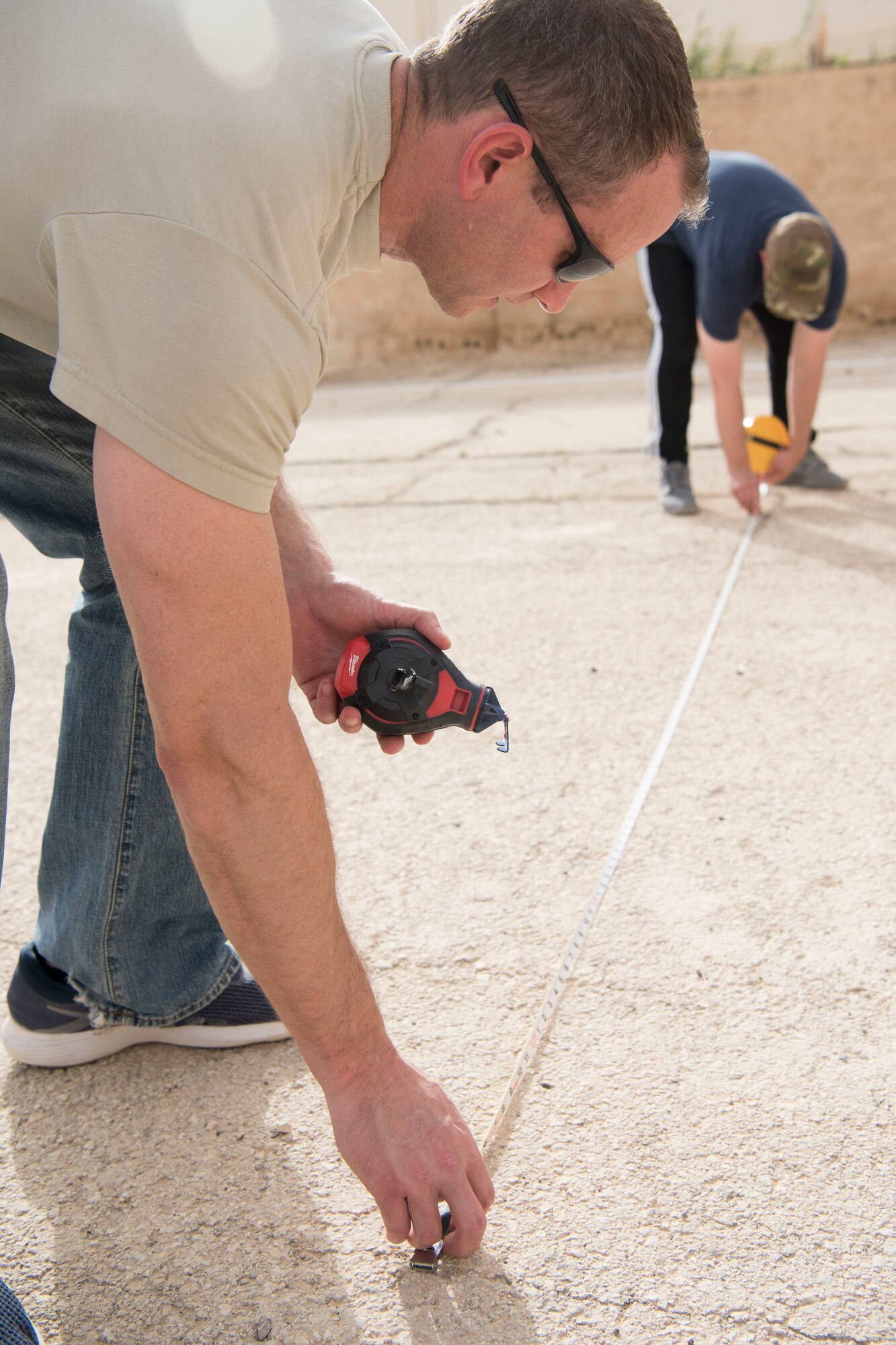 Lt. Col. Shane McCauley, 332nd Expeditionary Medical Group deputy commander, measures out dimensions for a soccer field they are renovating for a local elementary at an undisclosed location in Southwest Asia May 26, 2018.