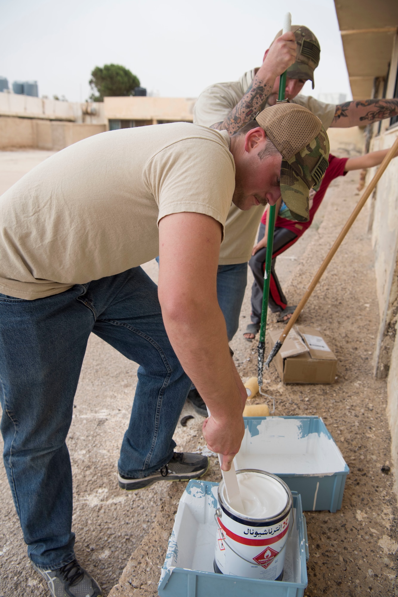 332nd Expeditionary Medical Group Airmen mix paint for a soccer field they are renovating for local kids at an undisclosed location in Southwest Asia May 26, 2018.