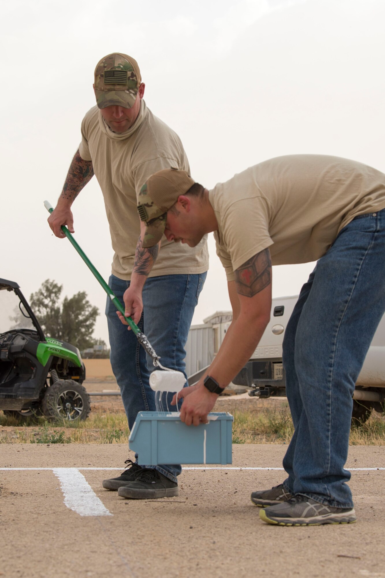332nd Expeditionary Medical Group Airmen paint lines for a soccer field they are renovating for local elementary school at an undisclosed location in Southwest Asia May 26, 2018.