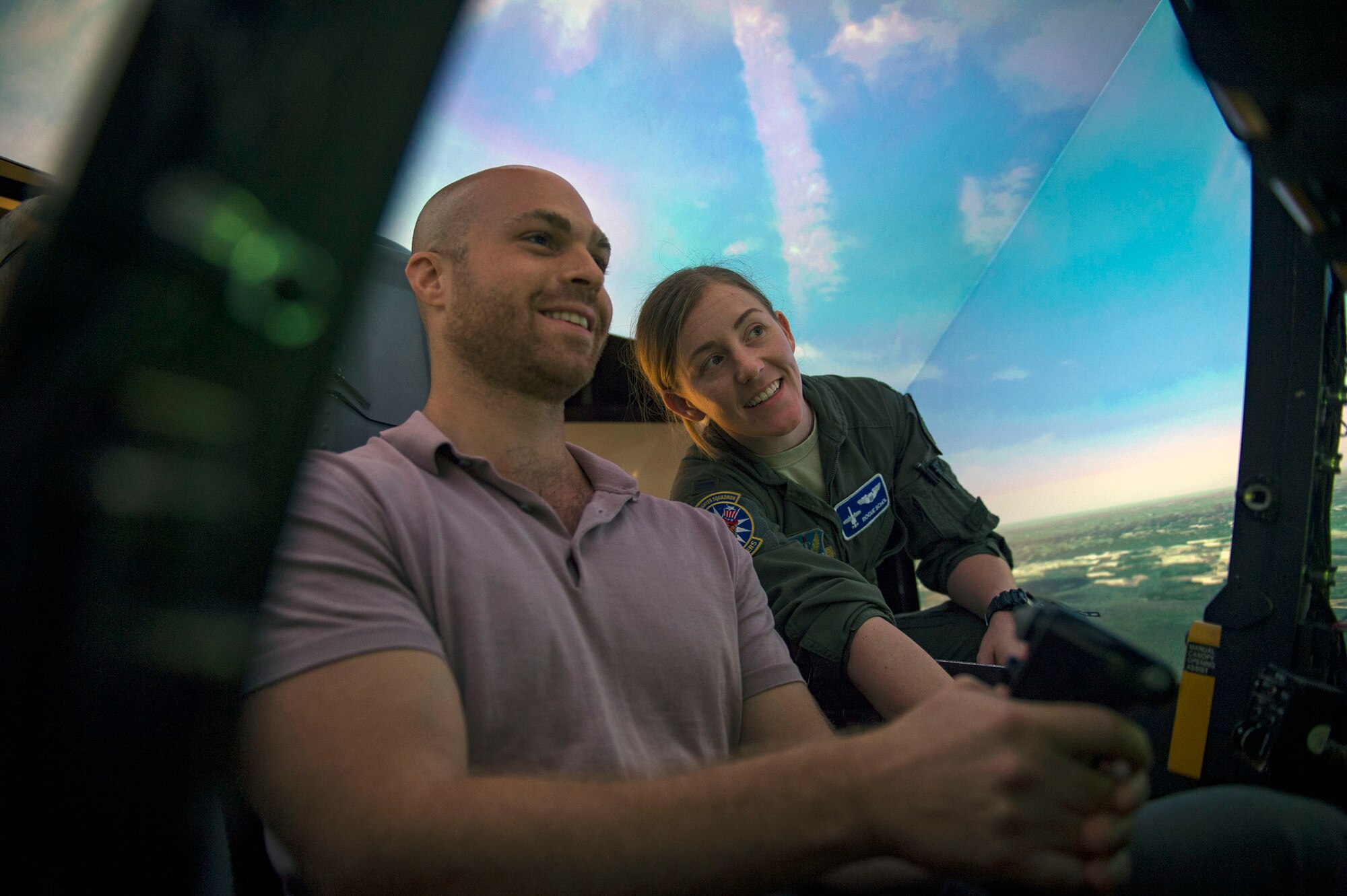 1st Lt. Laney Schol, right, 74th Fighter Squadron A-10C Thunderbolt II pilot, instructs Gavin Harnett, RAND associate physical scientist, as he flies in an A-10 simulator, Aug. 8, 2018, at Moody Air Force Base, Ga. RAND integrated with Moody’s rescue, flying and maintenance professionals to examine firsthand Air Force operations. This familiarization helps RAND develop their analysis to ultimately present policy recommendations to Air Force decision makers. Since 1948, RAND has performed analysis for the U.S. Air Force. (U.S. Air Force photo by Senior Airman Greg Nash)