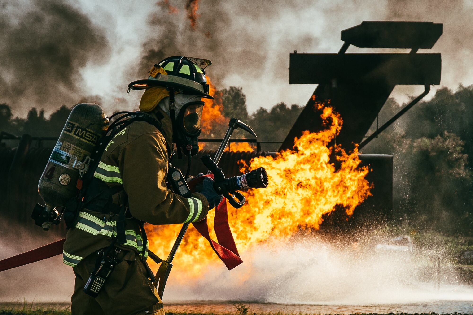 Senior Airman William Leuzinger, 11th Civil Engineer Squadron fire and emergency services firefighter, pulls a fire hose toward a simulated aircraft fire during a training exercise at Joint Base Andrews, Md., Aug. 9, 2018. During the training, firefighters were split into three teams of two, with two teams extinguishing fires and the remaining team on standby. (U.S. Air Force photo by Staff Sgt. Delano Scott)