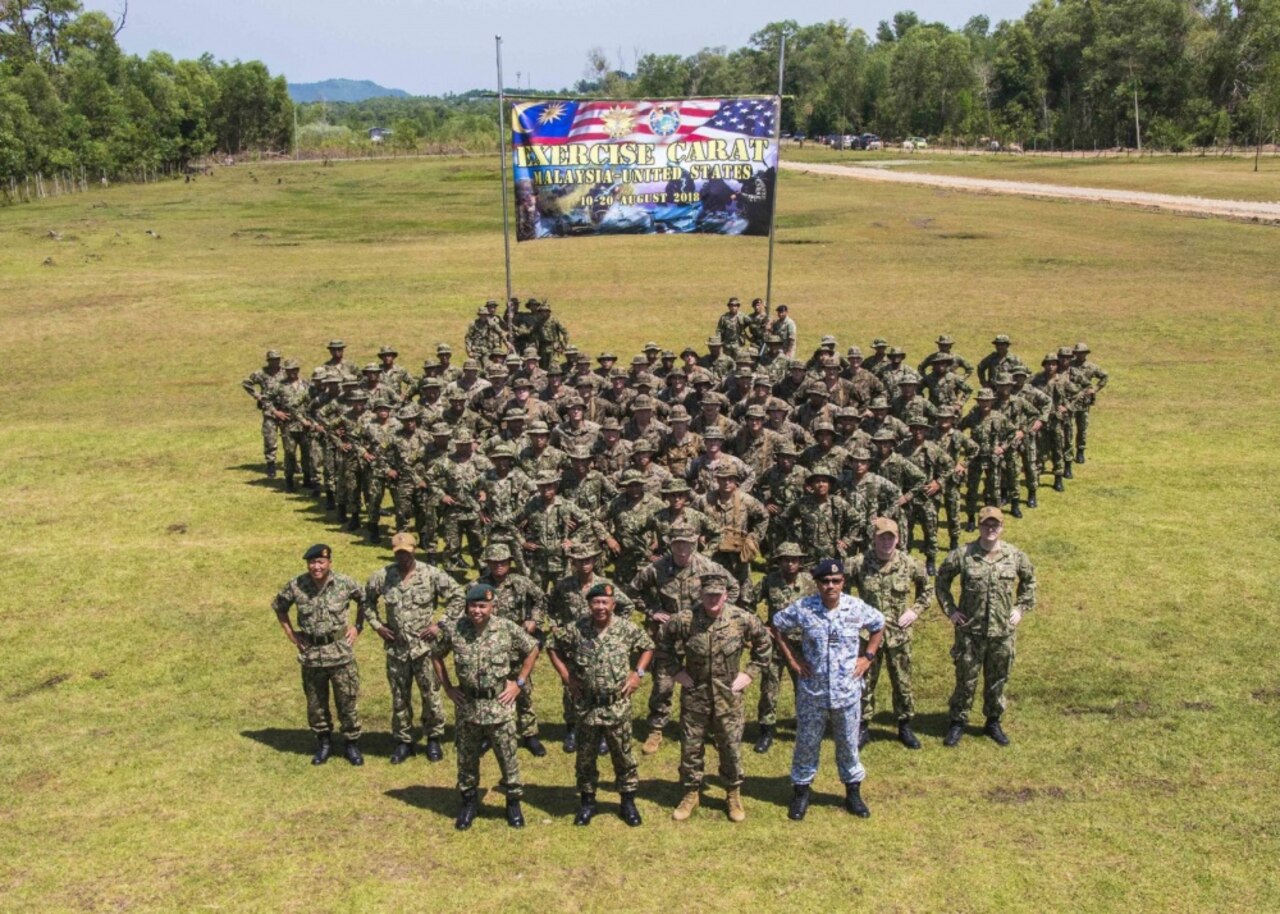 U.S. Marines stand in formation with Marines from the Royal Malaysian Navy for a photo during the opening ceremony of Cooperation Afloat Readiness and Training on Kota Belud Marine Base, Malaysia.