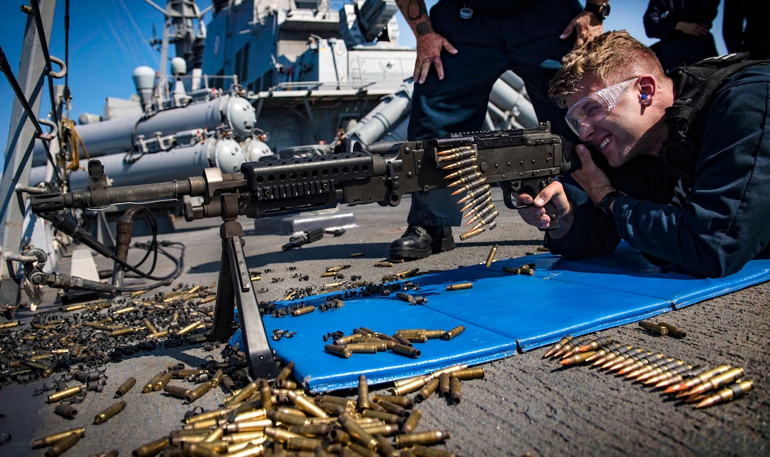 A sailor fires an M240B machine gun during live-fire.