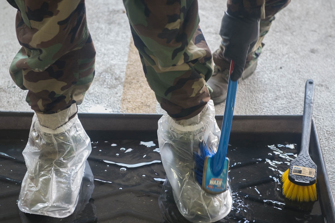 A U.S. Air Force Airman, cleans protective booties during an Aircrew Contamination Control Area training at Joint Base Langley-Eustis, Virginia, July 12, 2018. Aircrew flight equipment career field trainers travel to various installations to ensure unit proficiency and standardization across the Air Force.