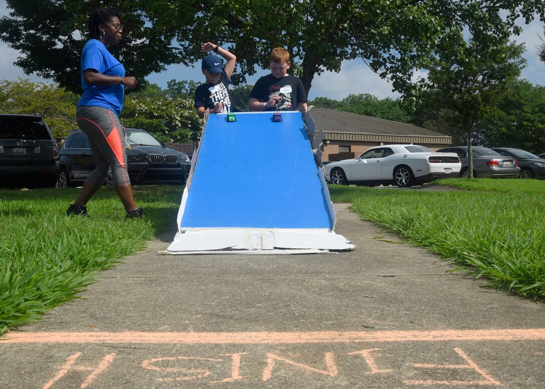 Ethan McMickle, center, and David Clark, right, race their hand-painted derby cars at the 7th Annual Exceptional Family Member Program Summer Camp Experience at Joint Base Andrews, Md., Aug. 9, 2018. Camp attendees completed a variety of activities related to STEM throughout the week-long camp. (U.S. Air Force photo by Senior Airman Abby L. Richardson)
