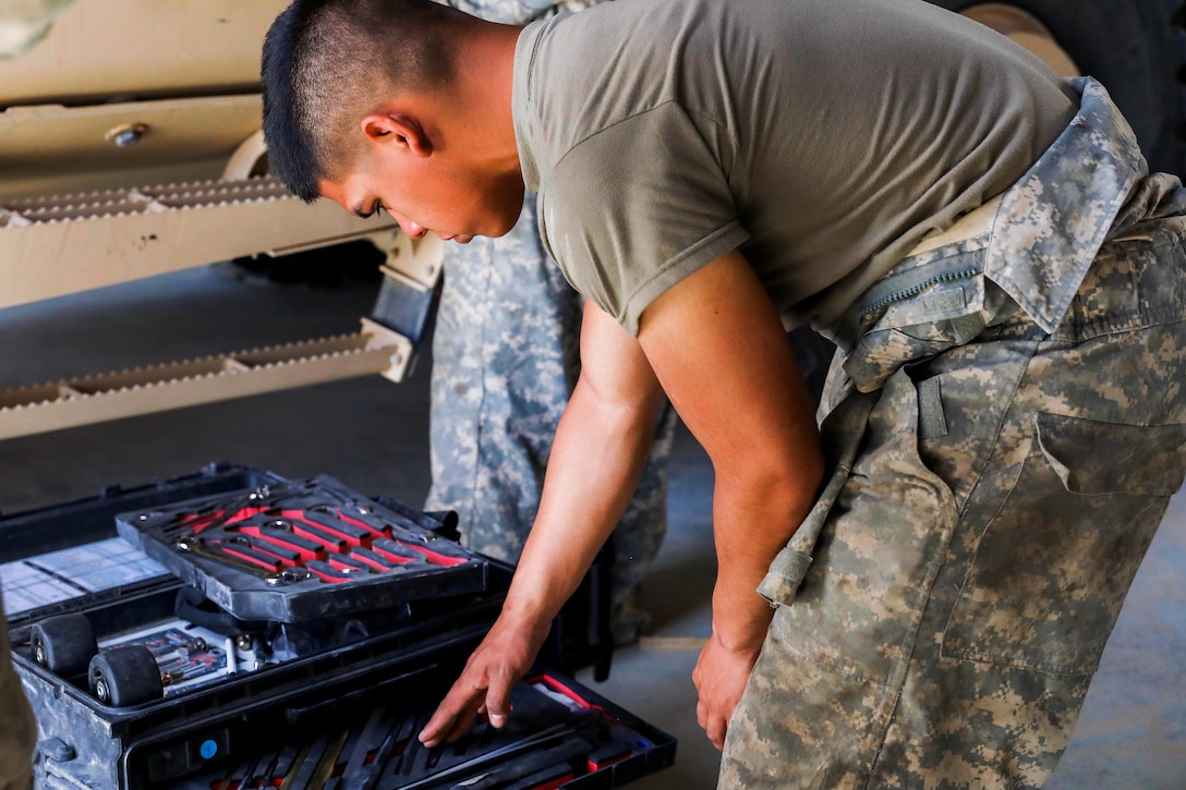 A soldier looks through his toolbox before repairing a tactical vehicle in a motor pool.