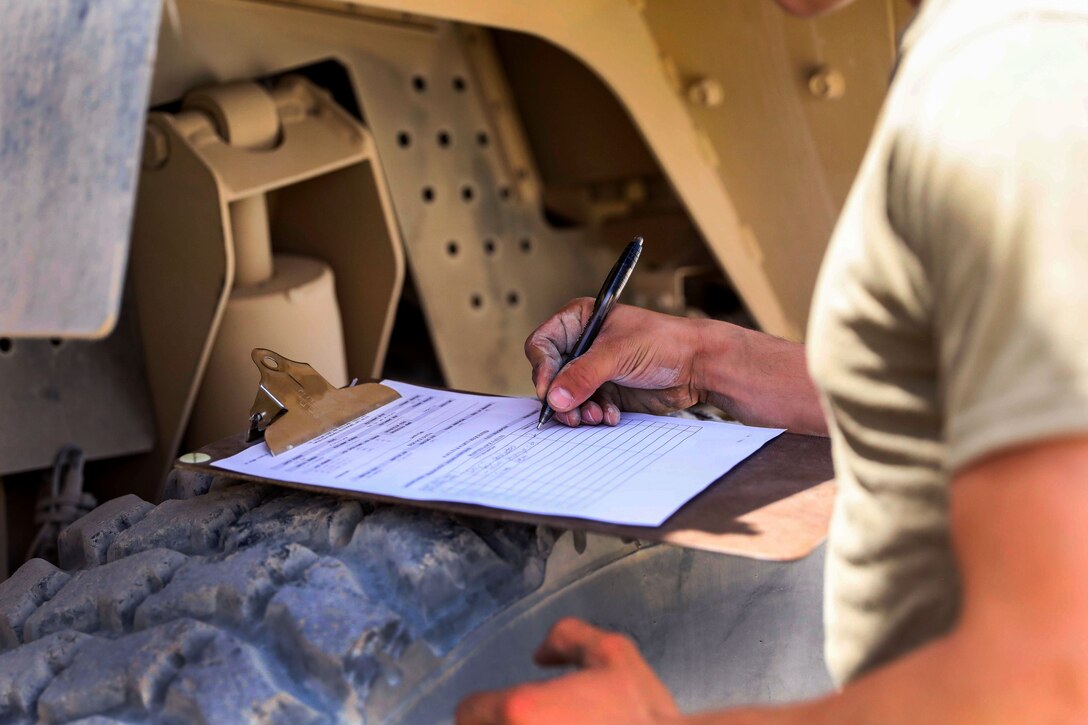 A soldier fills out a form after performing maintenance checks on a tactical vehicle.