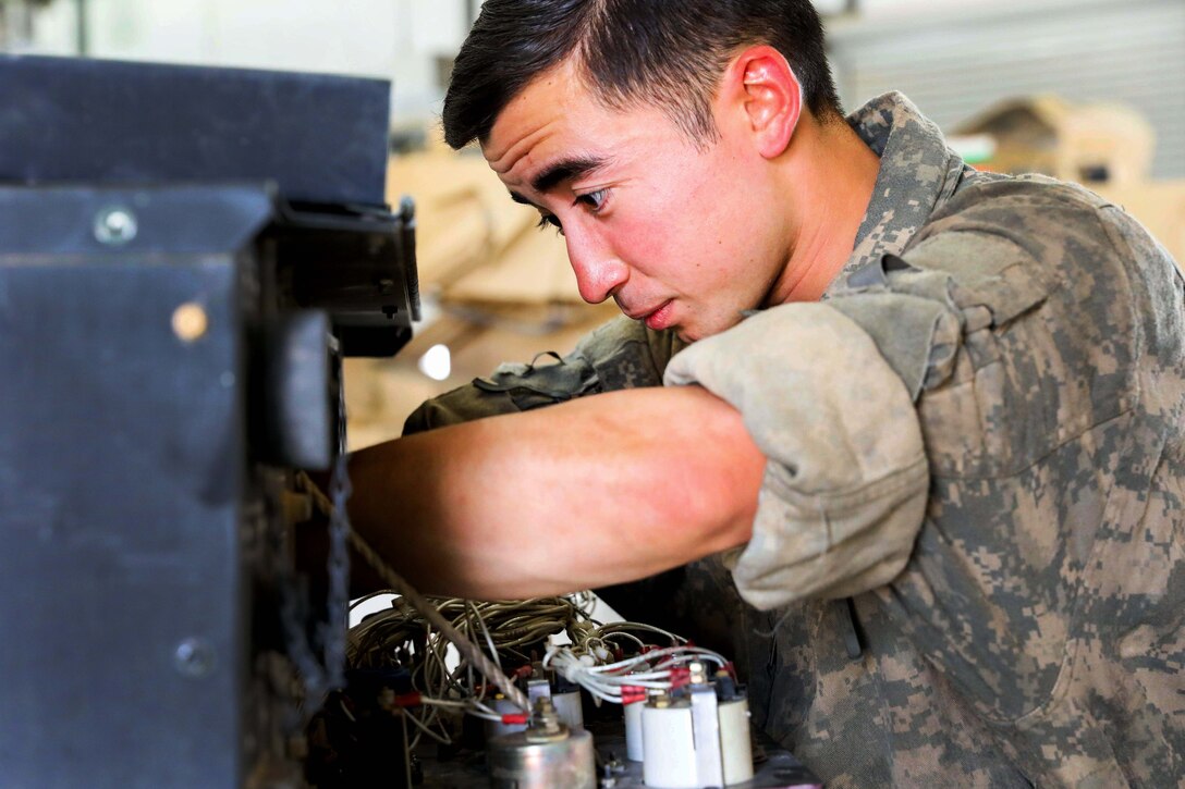 A soldier performs preventive maintenance checks and services on a generator.